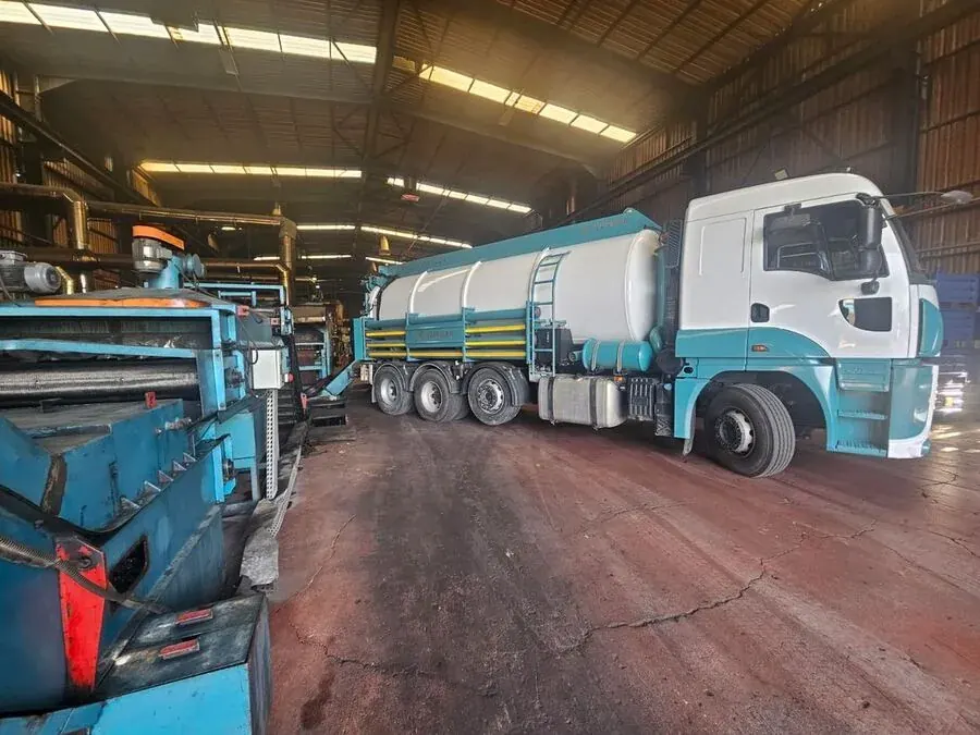Üç dingilli vakumlu vidanjör aracı, sanayi tesisi içinde çalışma pozisyonunda